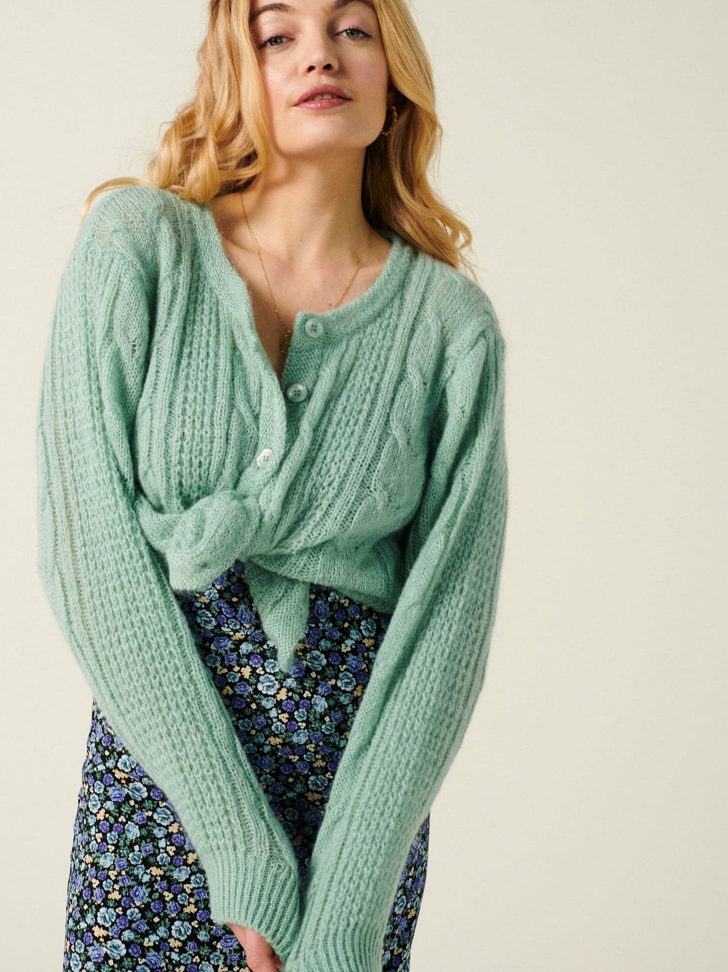 Green cable knit cardigan paired with a floral skirt