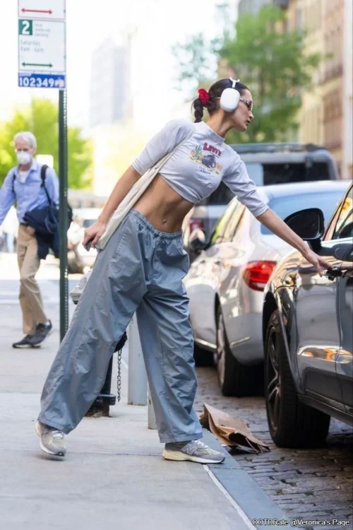 Bella Hadid Casual Streetwear: Cropped Graphic Tee with Gray Parachute Pants and Sneakers