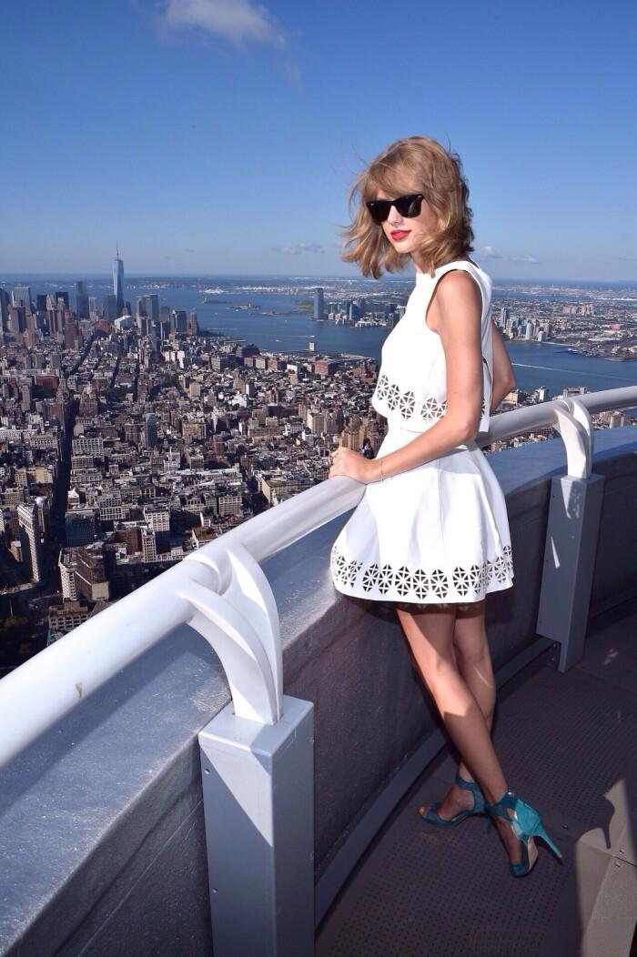 Taylor Swift in white lace-up dress and blue heels