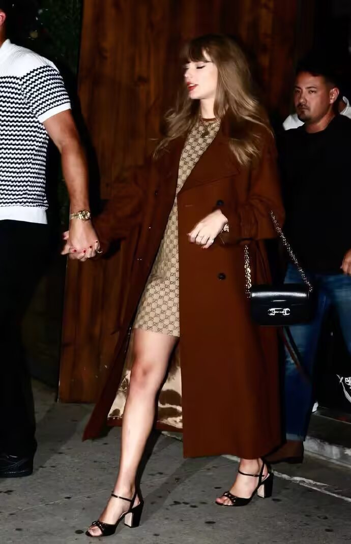 Taylor Swift in plaid mini dress with brown coat and heels