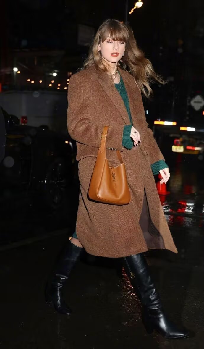 Taylor Swift in camel coat, green sweater, and black over-the-knee boots