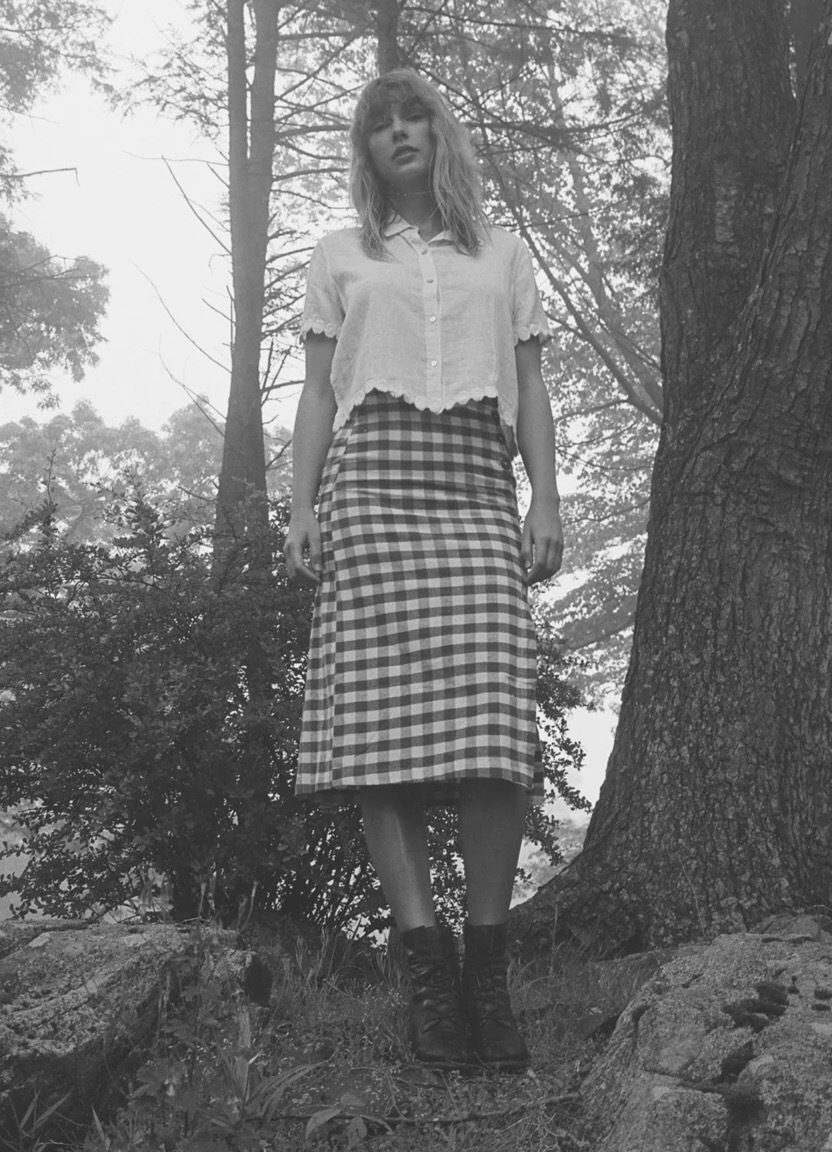 Taylor Swift in white shirt and plaid midi skirt with boots outdoors