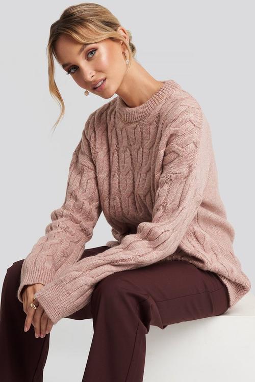 Women's cable knit sweater paired with tailored pants
